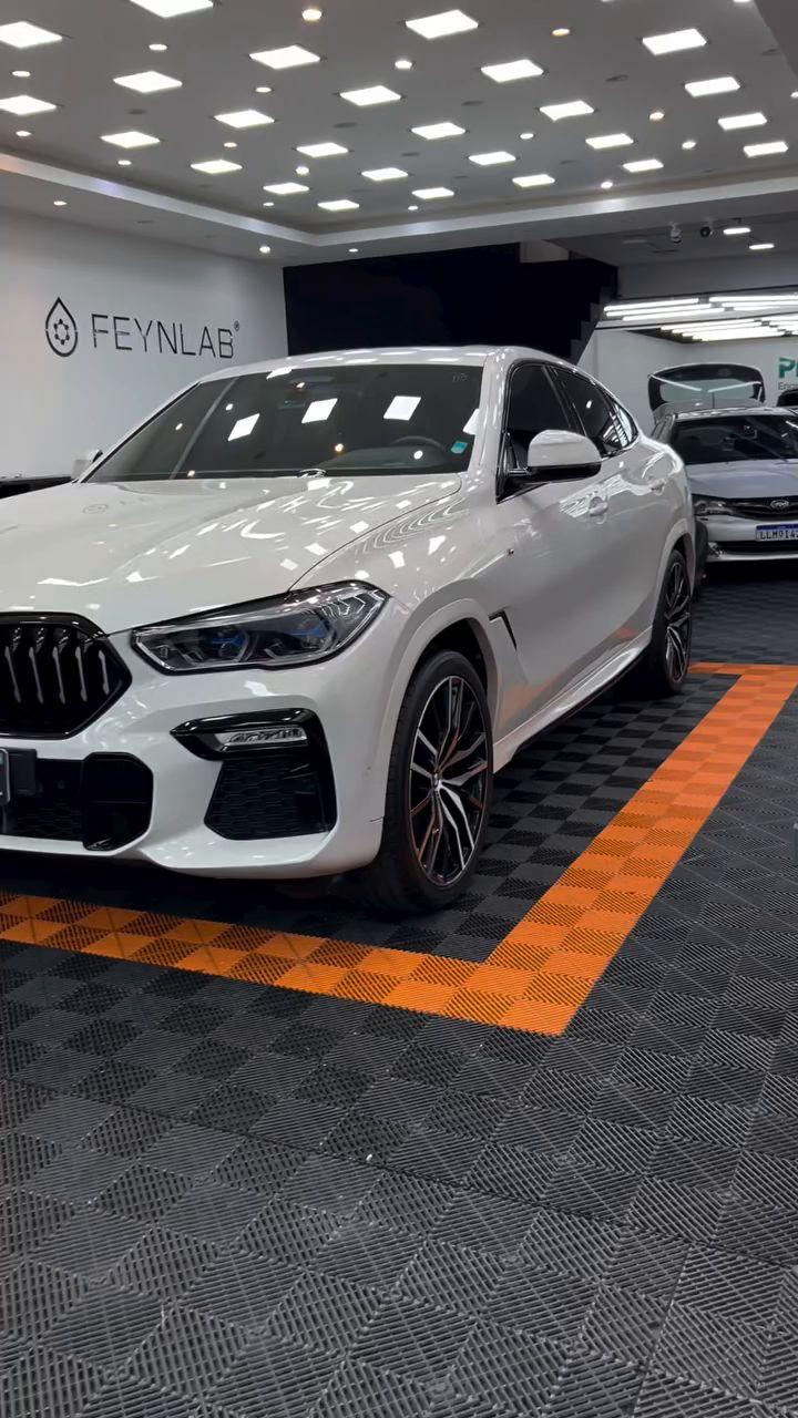 BMW X6 branco no estúdio, sobre o piso laranja e preto